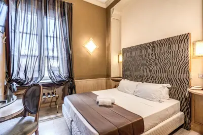 a hotel room with a bed and a table and window at Hotel Nardizzi Americana in Rome
