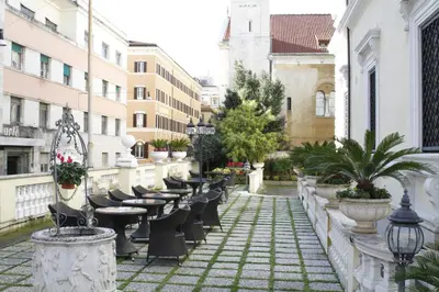 an outdoor patio with tables and chairs and buildings at Hotel Villa Pinciana in Rome