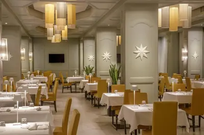 a restaurant with white tables and yellow chairs at Grand Hotel Fleming by OMNIA hotels in Rome
