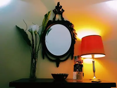 a table with a lamp and a mirror on a wall at 4 You City Center Apartament in Rome