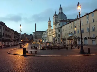a city street with benches and buildings at night at Hotel Teatro Pace in Rome