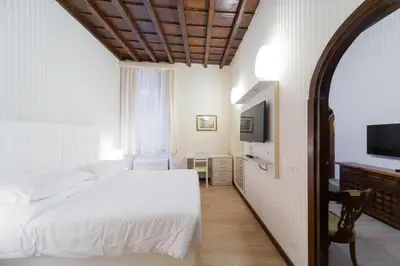 a bedroom with a white bed and a flat screen tv at Trevi 41 Hotel in Rome