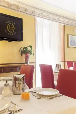 a table with red chairs and a dining room at Hotel Tuscolana in Rome