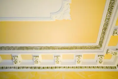 a room with a yellow wall with a white ceiling at Hotel Tuscolana in Rome