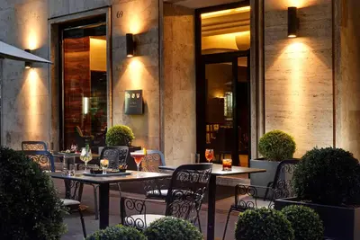 a restaurant with tables and chairs in front of a building at UNA Hotels Decò Roma in Rome