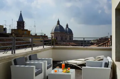 a balcony with chairs and a table and a building at UNA Hotels Decò Roma in Rome