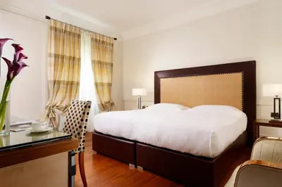 a bedroom with a large bed and a desk and a table at UNA Hotels Decò Roma in Rome