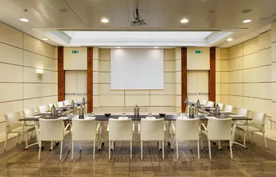 a conference room with tables and chairs and a white screen at UNA Hotels Decò Roma in Rome