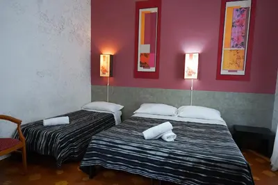 two beds in a room with red walls at Roma Room Hotel in Rome