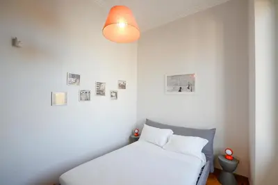 a white bedroom with a bed and a lamp at Fontana Più Stella in Rome