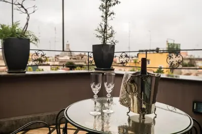a glass table with two wine glasses on a balcony at Hotel Antica Locanda in Rome