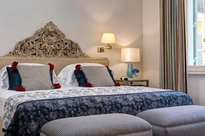 a bedroom with a king sized bed with two chairs at Rocco Forte Hotel De Russie in Rome