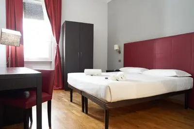 a bedroom with a large bed with a red headboard at Target Inn Rooms in Rome