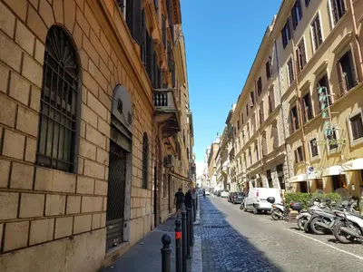 two people walking down a street next to buildings at Via Veneto Prestige Rooms in Rome