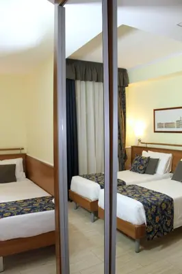 a hotel room with two beds and a mirror at Hotel Windrose in Rome