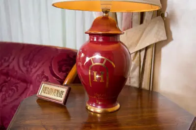 a red vase sitting on a table next to a lamp at Hotel Arco Di Travertino in Rome