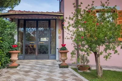 a pink house with a door and a tree at Hotel Arco Di Travertino in Rome