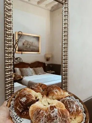 a person holding a plate of bread in front of a mirror at Residenza Sciarra Suites in Rome
