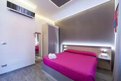 a bedroom with a pink bed with shoes on it at Guesthouse Pop in Rome