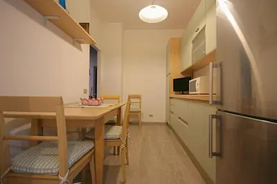 a small kitchen with a table and a refrigerator at Casa di Angela in Rome
