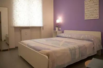 a bedroom with a white bed with a purple wall at DaNoi in Trastevere in Rome