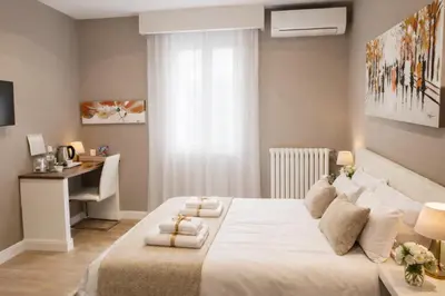 a bedroom with a white bed and a desk at Tollì rooms in Rome