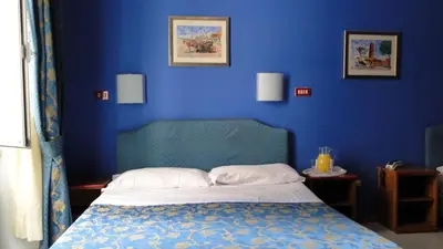 a blue bedroom with a bed with a blue wall at Hotel Altavilla Dieci in Rome