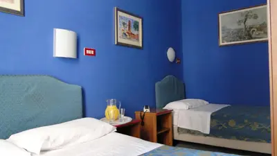 a room with two beds and a blue wall at Hotel Altavilla Dieci in Rome