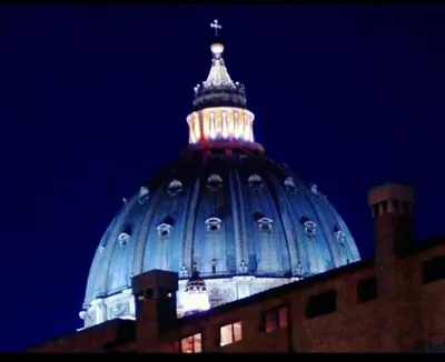 a dome of a building with a cross on top at night at Vatican View Apartment in Rome