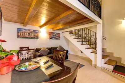 a living room with a dining table and a staircase at Aurelia Vatican Apartments in Rome