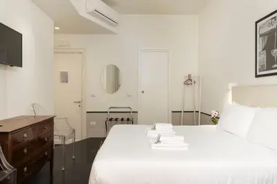a bedroom with a white bed with a dresser and a mirror at Gatsby Guest House - Zen 60 in Rome
