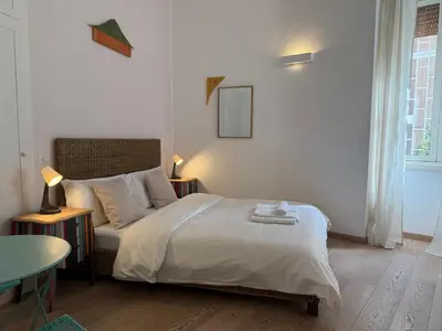 a white bedroom with a bed and a table at Green Rooms Trastevere in Rome