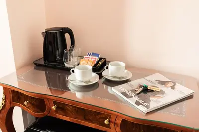 a table with two cups and a coffee pot and a magazine at Queen Meg Roma in Rome