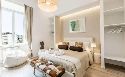 a white bedroom with a large bed and a chair at Thebestinrome Piazza di Spagna in Rome