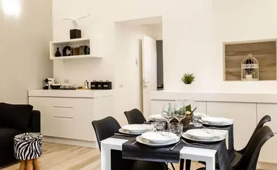 a dining room table with black chairs and a white kitchen at Thebestinrome Piazza di Spagna in Rome