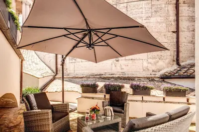a large umbrella in a patio with chairs and a table at Eitch Borromini Palazzo Pamphilj in Rome