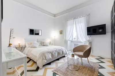 a white bedroom with a bed and a chair at Living Rome Repubblica apartment in Rome