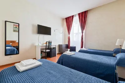 a hotel room with two beds and a flat screen tv at Roma Enrico Guesthouse in Rome