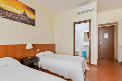 a hotel room with two beds and a bathroom at Roma Enrico Guesthouse in Rome