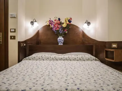 a bedroom with a bed with a vase of flowers at Hotel 4 Coronati in Rome