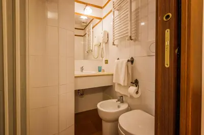 a white bathroom with a toilet and a sink at Hotel 4 Coronati in Rome