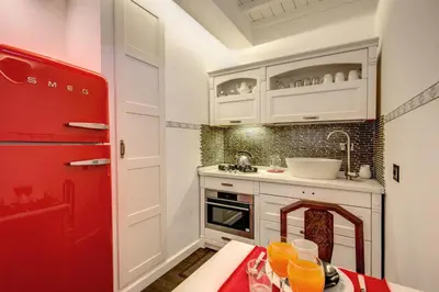 a kitchen with white cabinets and a red refrigerator at Campo de' Fiori Stylish White in Rome