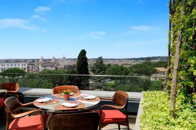 a table and chairs on a balcony with a view at Hotel Eden - Dorchester Collection in Rome