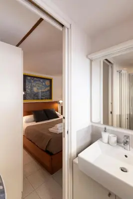 a bedroom with a bed and a sink and a mirror at Colosseum Cottage in Rome