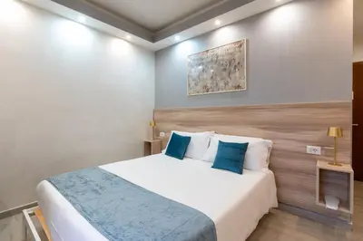 a bedroom with a large white bed with blue pillows at Leone D'Oro GUESTHOUSE - close to Piazza Vittorio in Rome