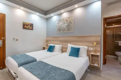 two beds in a hotel room with blue pillows at Leone D'Oro GUESTHOUSE - close to Piazza Vittorio in Rome