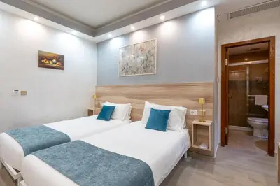 two beds in a hotel room with a bathroom at Leone D'Oro GUESTHOUSE - close to Piazza Vittorio in Rome