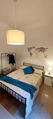 a bedroom with a bed with a blue pillow and a lamp at Apartment Ostiense Piramide Station in Rome
