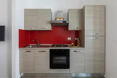 a kitchen with wooden cabinets and a red wall at Cornelia House in Rome