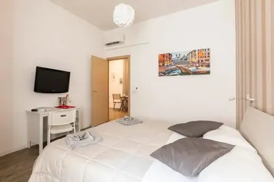 a white bedroom with a bed and a desk and a television at Cornelia House in Rome